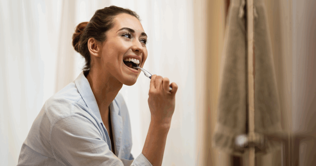 Electric toothbrush and manual toothbrush placed side by side on bathroom counter